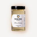 Jar of Miere Pe Bune Salcam honey showing golden color and wooden honey dipper in a clear glass jar.